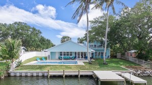 A house with a pool, a covered patio, and a dock extending into the water. - Canal-Front Home with Heated Pool (Cocoa Beach)