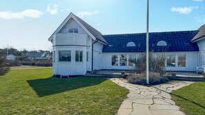 Une maison à deux étages avec un toit bleu et un revêtement extérieur blanc.
