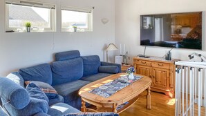 Un salon avec un canapé bleu, une table basse en bois, un téléviseur et un radiateur.