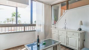 A room with a glass-top table, a white cabinet, and a view of palm trees through large windows. - 2 bedroom lovely apartment in Miramar (Miramar)