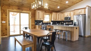 Una cocina moderna con armarios de madera, una isla central con taburetes y electrodomésticos de acero inoxidable.