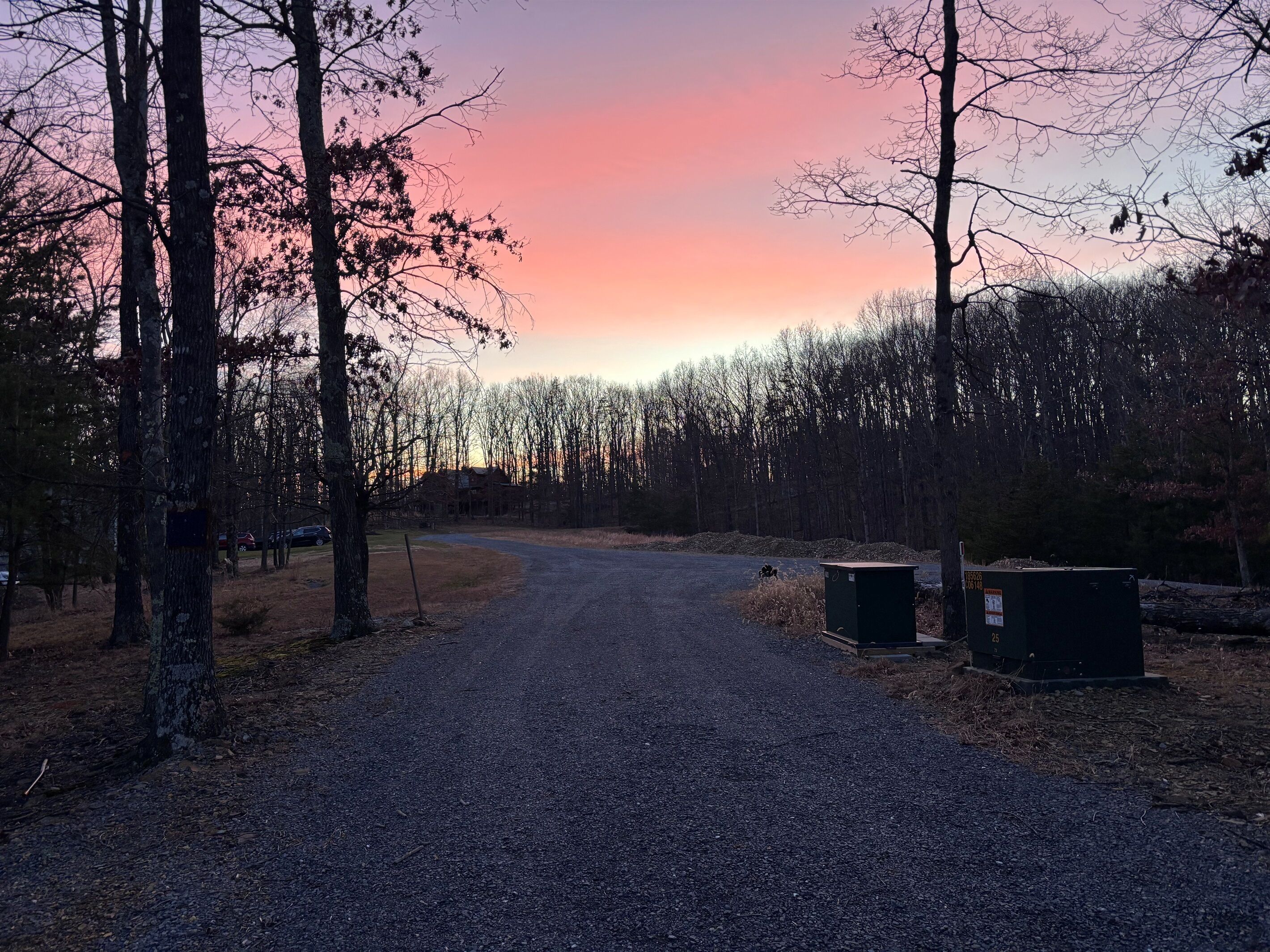 Soralla päällystetty polku, joka kulkee metsäisen alueen läpi, ja taustalla näkyy auringonlasku.