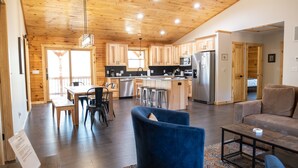 Una cocina moderna con armarios de madera, un refrigerador de acero inoxidable y una zona de comedor con mesa y sillas.