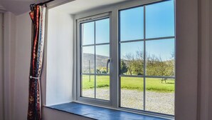 A room with a large window, a radiator, and a curtain. - 2 bedroom accommodation in St Clether, near Launceston (St Clether, near Launceston)