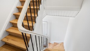 A wooden staircase with white handrails and a white wall.