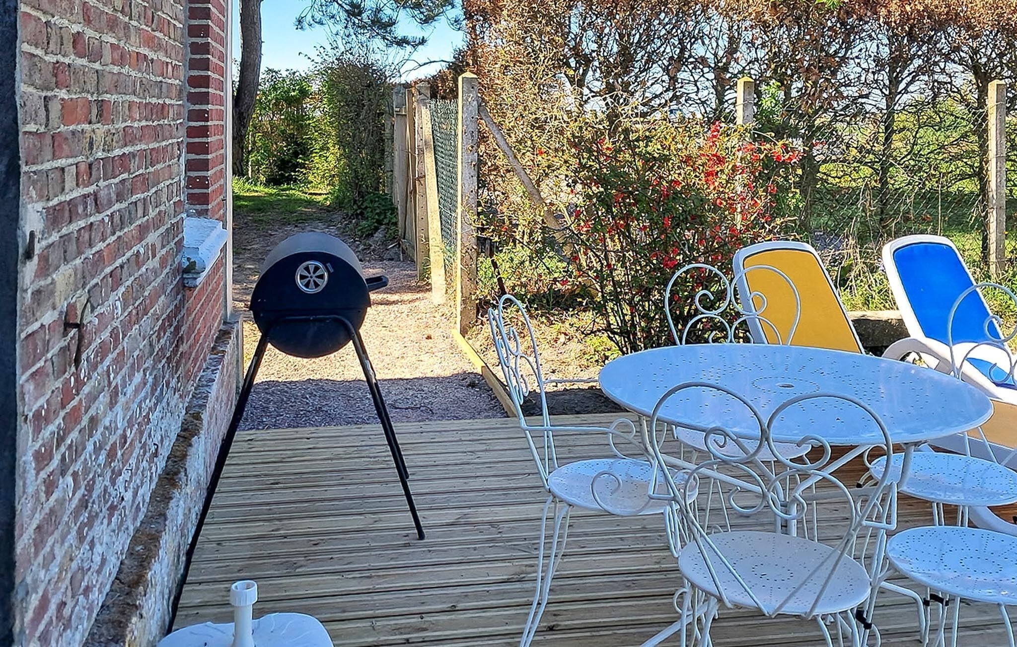A patio with a brick wall, a grill, and outdoor seating.