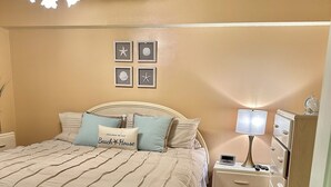 A bedroom with a large bed, a nightstand, a dresser, a ceiling fan, and wall decorations. - Breathtaking Ocean view, few steps to the beach!!!!! (Ocean City)