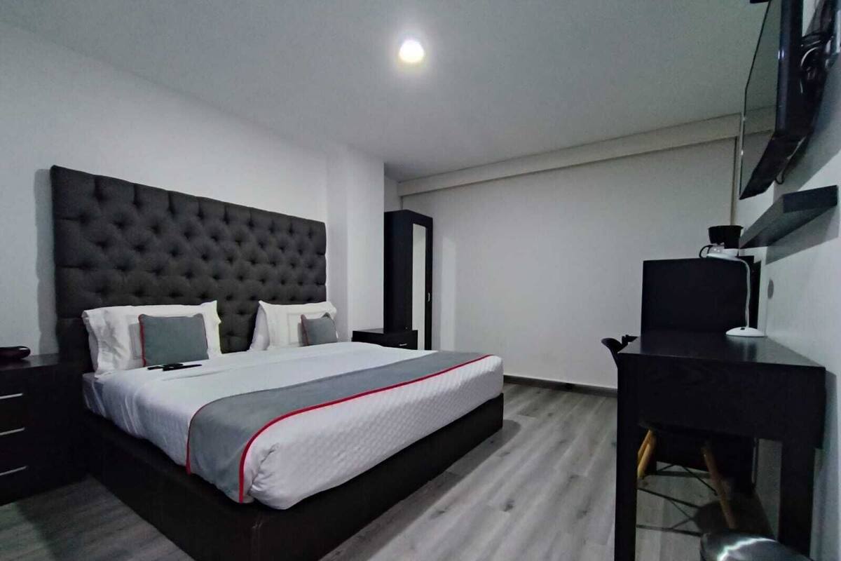 Una habitación de hotel moderna con una cama grande, un escritorio y una televisión.
