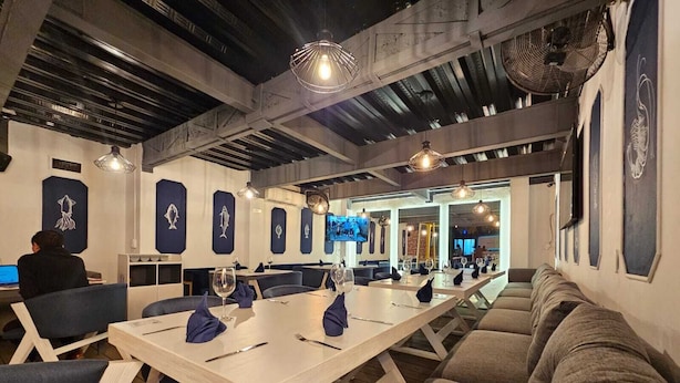 Un restaurante moderno con una larga mesa común, asientos individuales y un ambiente relajado.