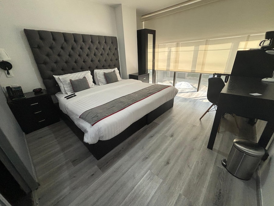 Ein modernes Schlafzimmer mit einem großen Bett, Nachttischen, einem Schreibtisch und Blick ins Freie.