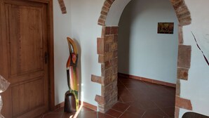 A hallway with a wooden door, a wooden sculpture, and a brick archway. - Spacious apartment strategically located for visiting Siena and province (Sovicille)