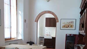 A dining area with a table and chairs, a kitchen in the background, and a patterned rug on the floor. - Spacious apartment strategically located for visiting Siena and province (Sovicille)