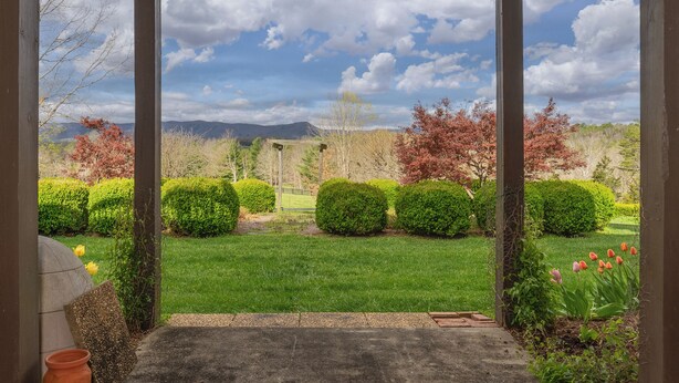 A covered outdoor area with a view of a well-maintained garden and distant mountains. - Duplex in Lexington, VA, Loranwoods (Rockbridge County)
