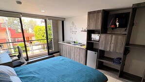 Een moderne slaapkamer met een groot bed, een kleine kitchenette en een televisie.
