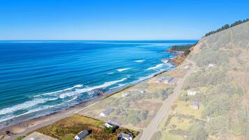 An aerial view of a coastal area with a clear road, a beach, and residential buildings.