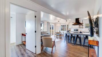 A spacious kitchen with a central island, bar stools, and a large window.