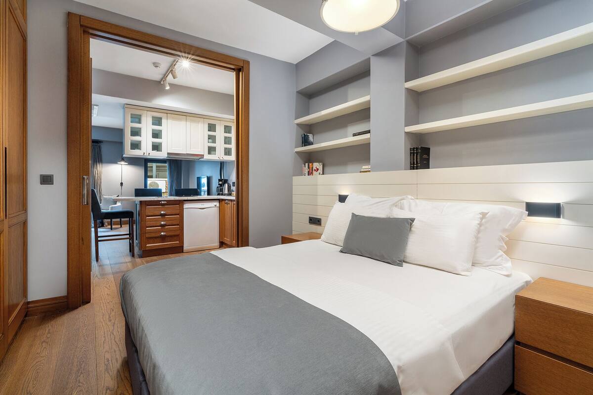 A modern bedroom with a large bed, bedside tables, and built-in shelving.