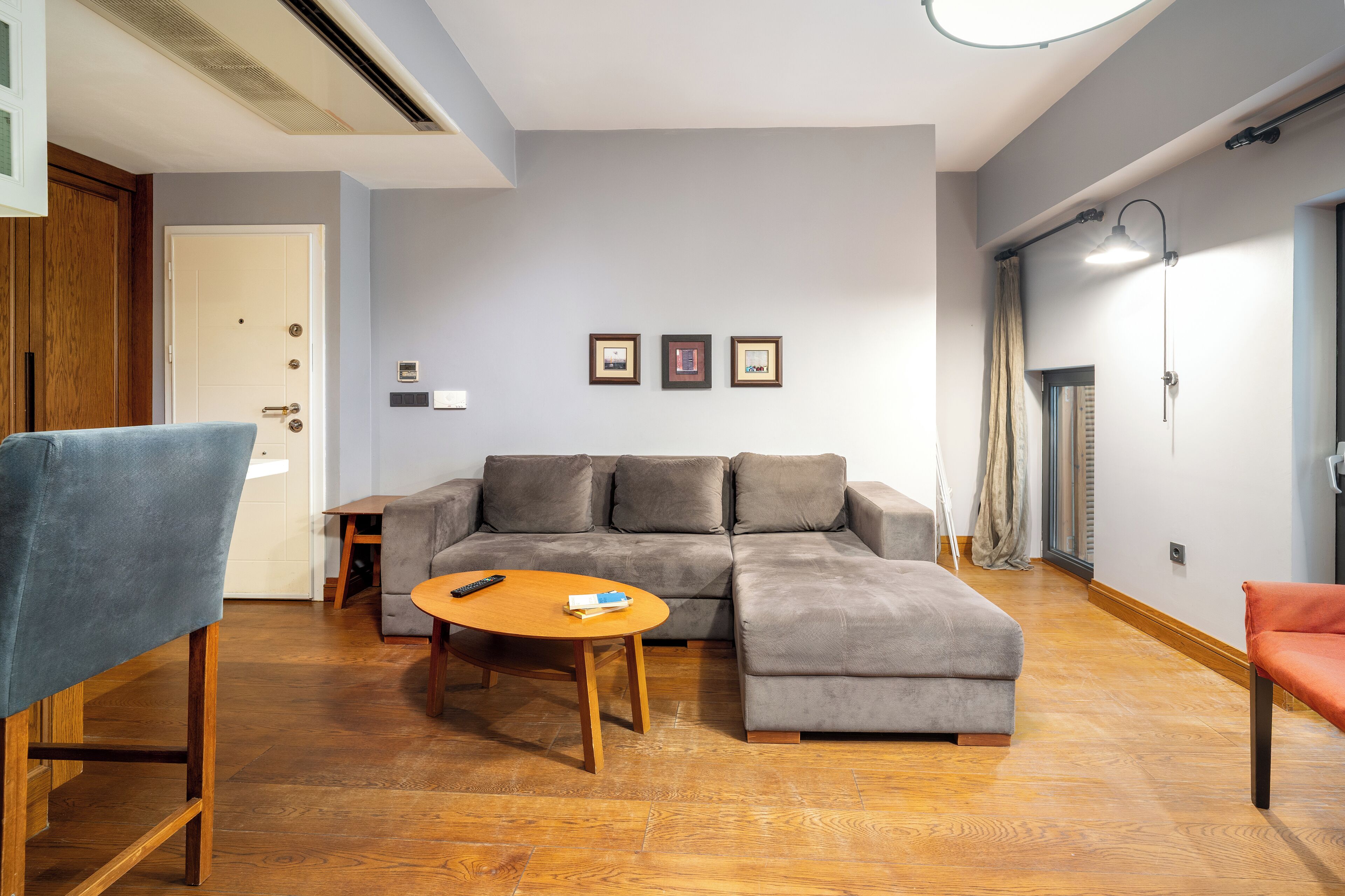 Un salon moderne avec un canapé d’angle, une table basse en bois et un fauteuil bleu.