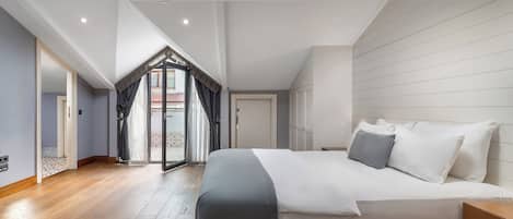 Ein Schlafzimmer mit einem großen Bett, Holzboden und einer geneigten Decke.