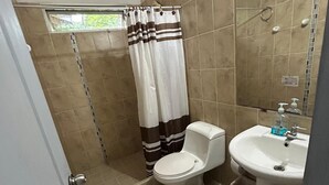 Une salle de bain avec douche, toilettes et lavabo.