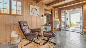 Una habitación acogedora con paredes de madera, chimenea, un ventanal y vistas al exterior.