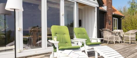 A deck with lounge chairs, a table, and a lamp.