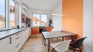 Eine moderne Küche mit Essbereich, großen Fenstern und Blick auf die Nachbarschaft.