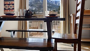 Un coin repas avec une table et des chaises, une vue sur une montagne et un tapis Navajo accroché au mur.