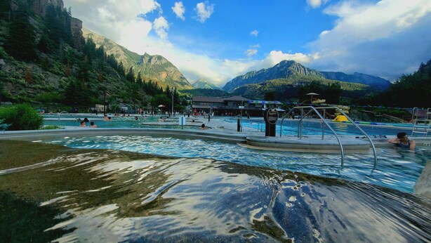 Une piscine dont l’eau est claire, entourée de montagnes et d’arbres.