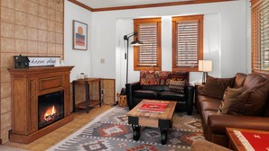 Un salon chaleureux avec une cheminée, un canapé en cuir, une table basse et un tapis à motifs.