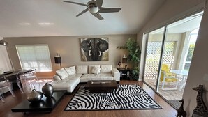 A modern living room with a sectional sofa, a zebra-patterned rug, and a ceiling fan. - Amazing pool house 10 minutes from disney (Kissimmee)