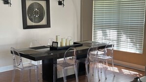 A dining area with a dark wooden table, clear chairs, and a centerpiece with candles. - Amazing pool house 10 minutes from disney (Kissimmee)
