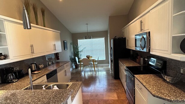 A modern kitchen with granite countertops, white cabinetry, and stainless steel appliances. - Amazing pool house 10 minutes from disney (Kissimmee)