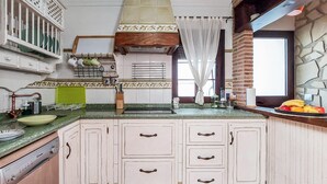 Een keuken met witte kastjes, een groen aanrecht, een spoelbak en een raam met gordijn.