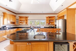A spacious kitchen with a central island, wooden cabinets, and a stainless steel refrigerator.
