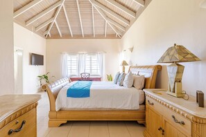 A bedroom with a bed, bedside tables, a TV, and a window with curtains.