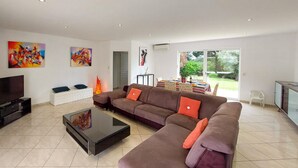 A modern living room with a sectional sofa, a flat-screen TV, a coffee table, and artwork on the walls. - Beautiful home in Léon (Léon)