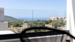 A view from a window overlooking a coastal landscape with a clear sky, a distant body of water, and a hilly terrain. - Amazing home in Primosten with sauna (Primosten)