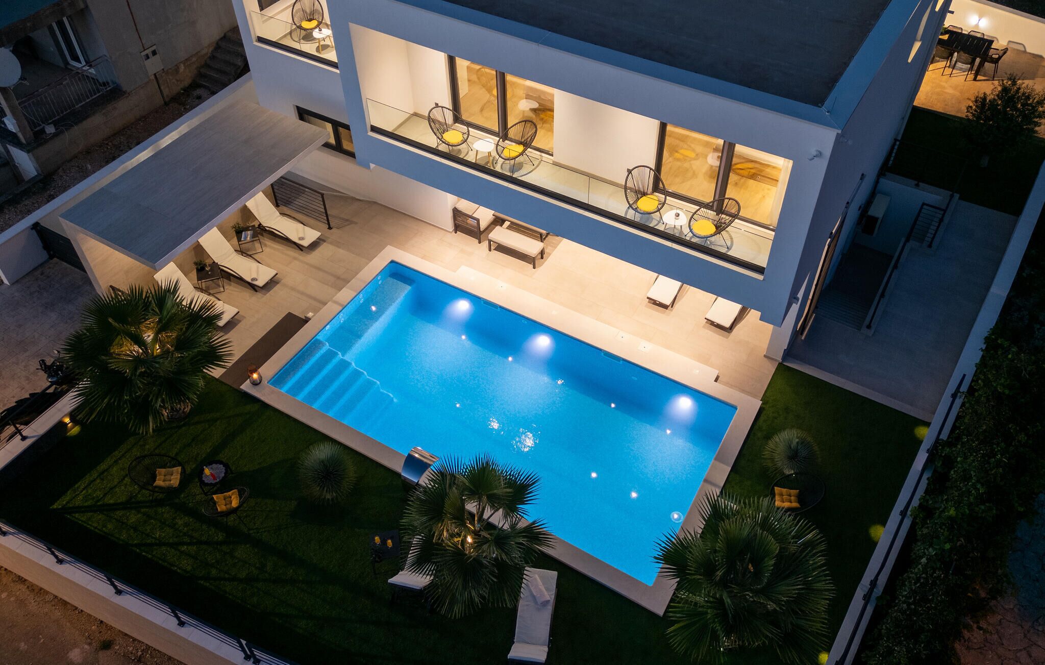 Ein modernes, zweistöckiges Gebäude mit Swimmingpool, Sitzgelegenheiten im Freien und einem gepflegten Rasen.
