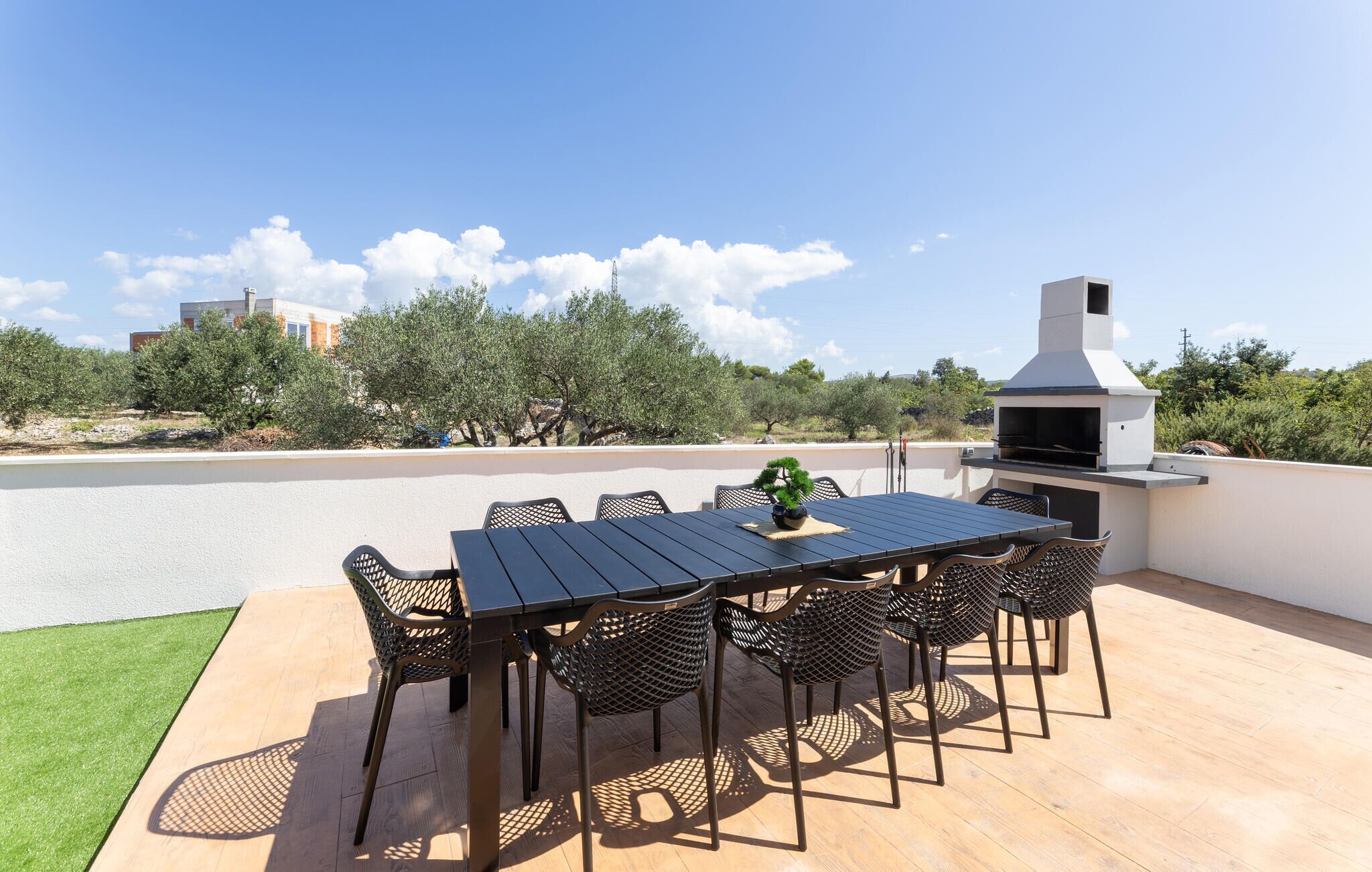 Une terrasse extérieure avec une table et des chaises, un barbecue et une vue sur le paysage environnant.