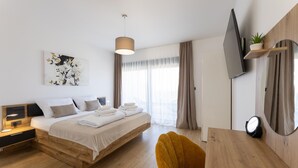 A modern bedroom with a bed, bedside table, lamp, artwork, and a TV mounted on the wall. - Amazing home in Primosten with sauna (Primosten)