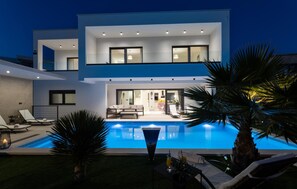 A modern two-story house with a swimming pool, lounge chairs, and a well-lit interior. - Amazing home in Primosten with sauna (Primosten)