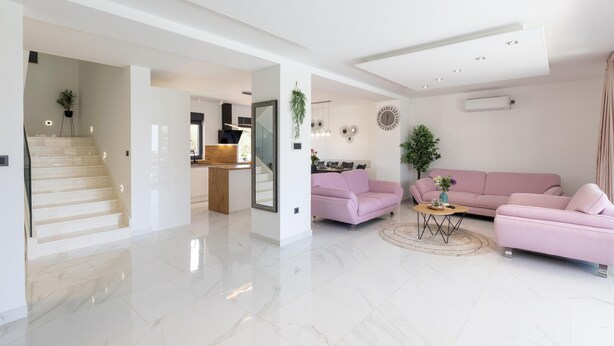 A modern interior with a staircase, a kitchen area, and a living room with a pink sofa and a round coffee table. - Amazing home in Primosten with sauna (Primosten)