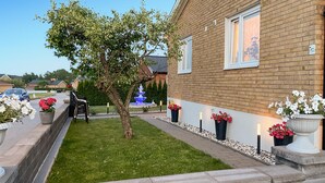 A residential garden with a lawn, a tree, a blue fountain, and flower planters along the pathway. - 2 bedroom amazing apartment in Vimmerby (Vimmerby)