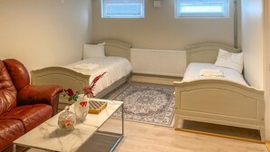 A bedroom with two beds, a leather chair, a small table with decorative items, and a patterned rug. - 2 bedroom amazing apartment in Vimmerby (Vimmerby)