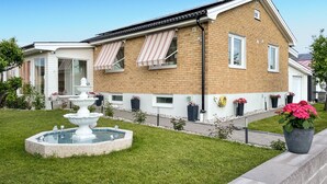 A residential building with a brick facade, a small garden with a fountain, and potted plants. - 2 bedroom amazing apartment in Vimmerby (Vimmerby)