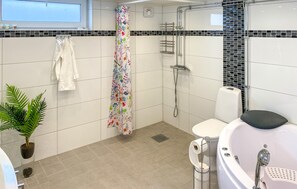 A modern bathroom with a shower, toilet, and bathtub.