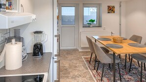 A compact kitchen with a blender, a refrigerator, and a dining area with a table and chairs. - 2 bedroom amazing apartment in Vimmerby (Vimmerby)