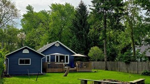 A blue house with a deck, surrounded by a wooden fence and lush greenery.