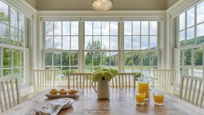 A dining area with a wooden table, white chairs, a pitcher of water, and a tray of muffins. - Secluded Estate Optional Guest House, Pond, Playroom, Gym & Theater Sunny Pond by Avantstay (Austerlitz)